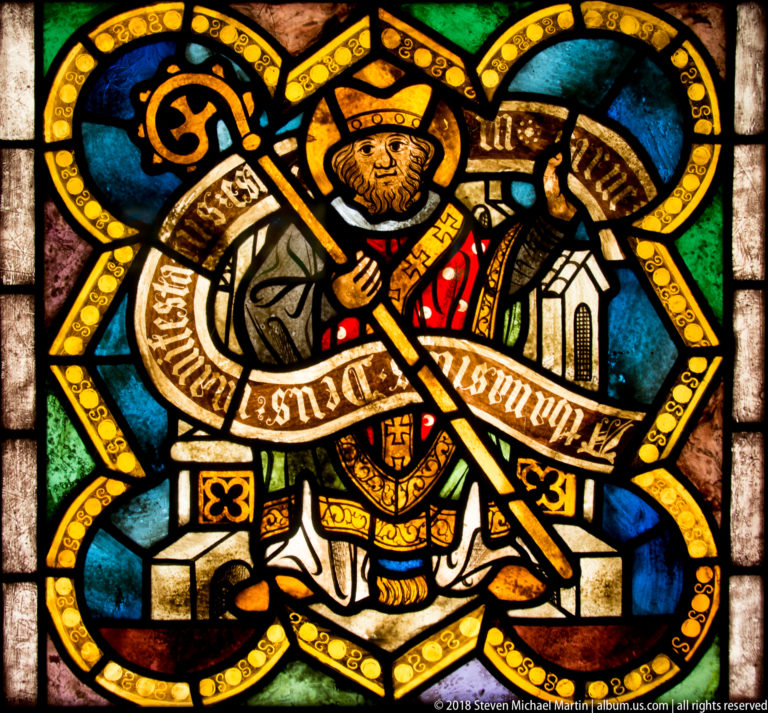 Saint Athanasius of Alexandria seated as a mitred bishop with crozier and architectural attribute in stained glass.