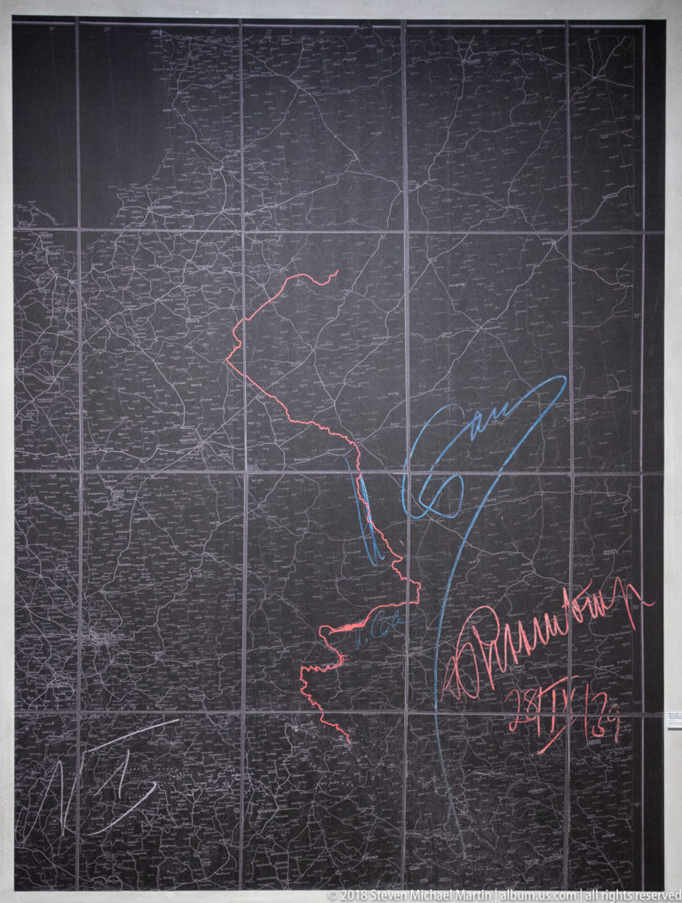Large dark map marked with red and blue routes, arrows, and handwritten-style annotations.
