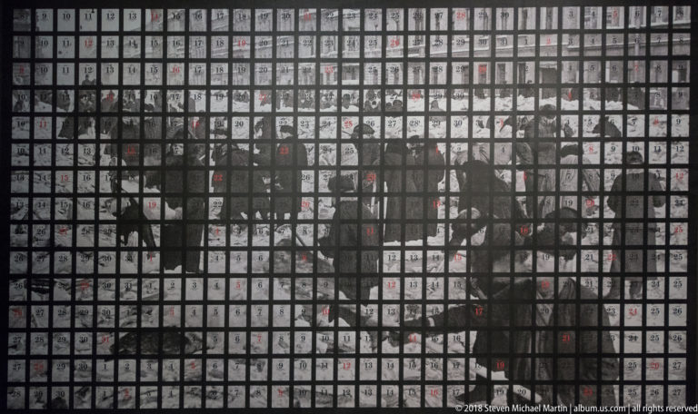 Historical prisoner photograph covered by a dense square grid with many small red and black numbers.