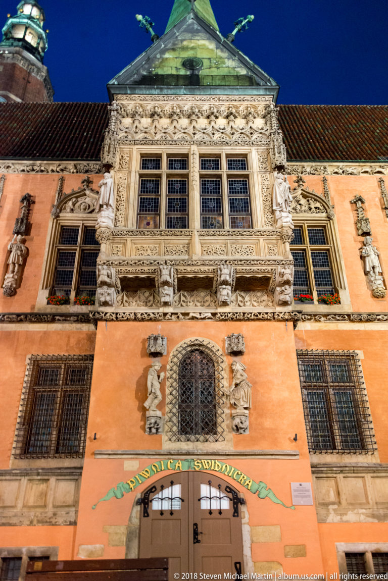Ornate Old Town Hall façade with carved stone windows, figural sculpture, heraldic decoration, and steep roof.