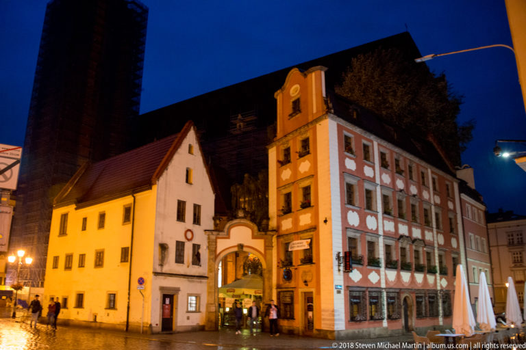 Narrow historic buildings with varied rooflines and a decorated façade stand near Wrocław Market Square at night.