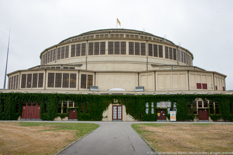 Centennial Hall’s broad concrete drum and tall window bands rise behind an ivy-covered lower wall and lawn.