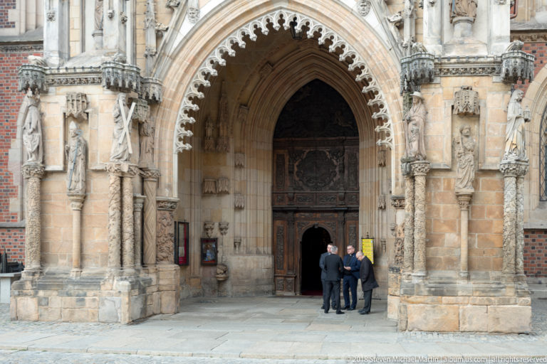 Deep pointed Gothic portal with carved standing figures and multiple stone archivolts at Wrocław Cathedral.