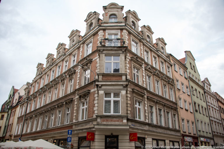 Ornate historic corner building with pilasters, balconies, carved window surrounds, and sculpted roofline.