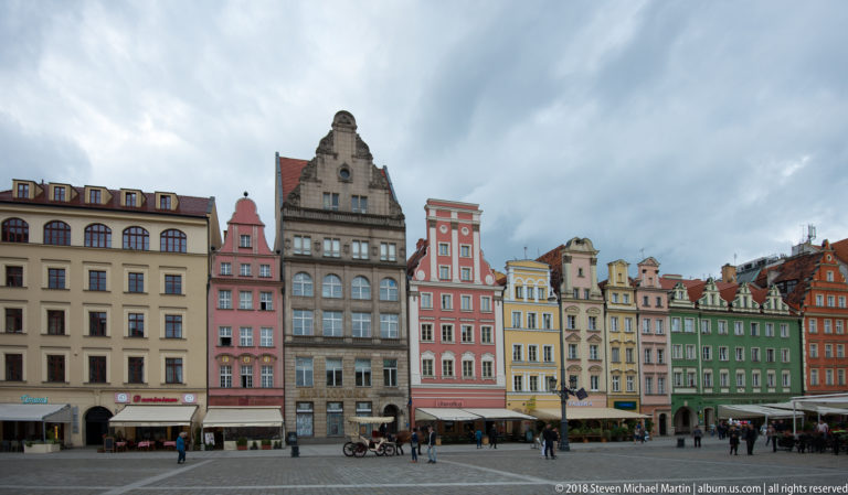 Colorful merchant houses with varied gables and shopfronts lining Wrocław Market Square.