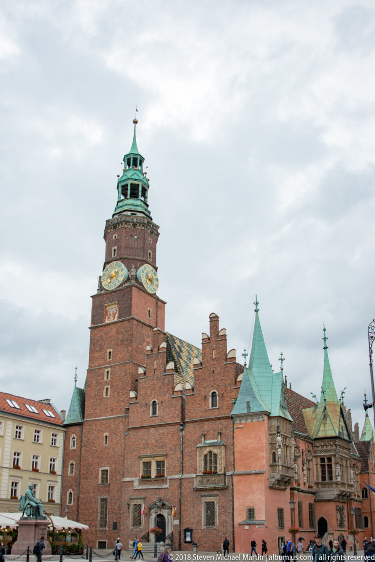 Broad view of Wrocław Old Town Hall with clock tower, stepped brick gables, stone bays, and copper roofs.