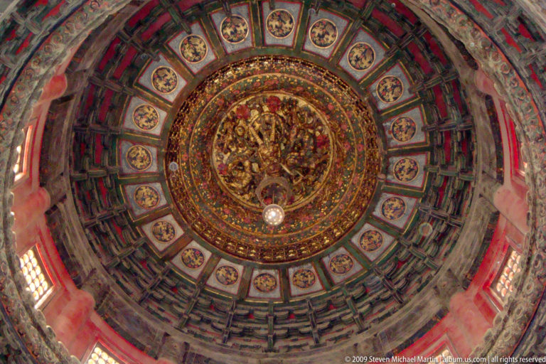 Upward view of an ornate caisson ceiling with concentric painted coffers surrounding a gilded central dragon medallion and repeating dragon roundels.