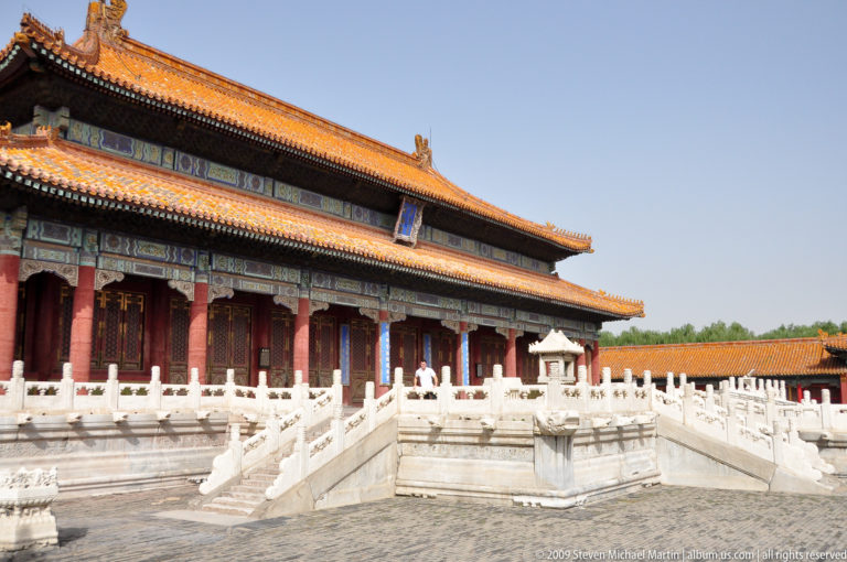 Oblique view of a yellow-roofed palace hall in the Forbidden City with red columns and white stone terraces and stairways in the eastern precinct.