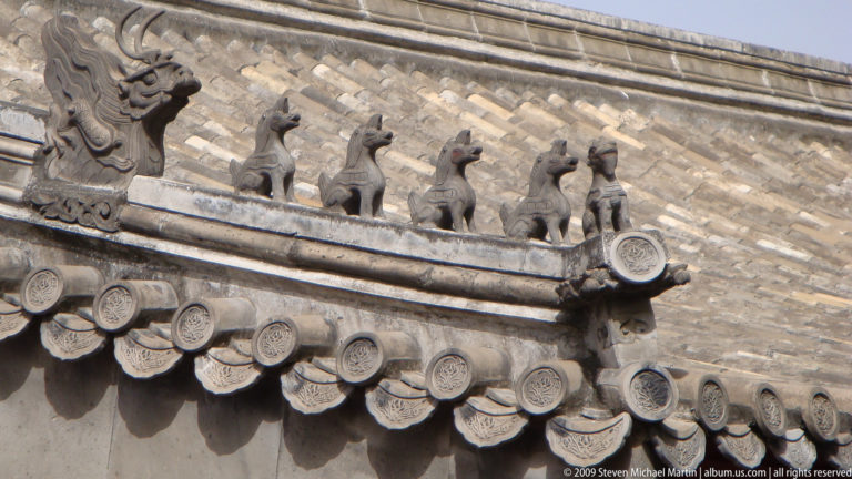 Close-up of gray ceramic animal roof figurines along the ridge of a secondary building in the Forbidden City.