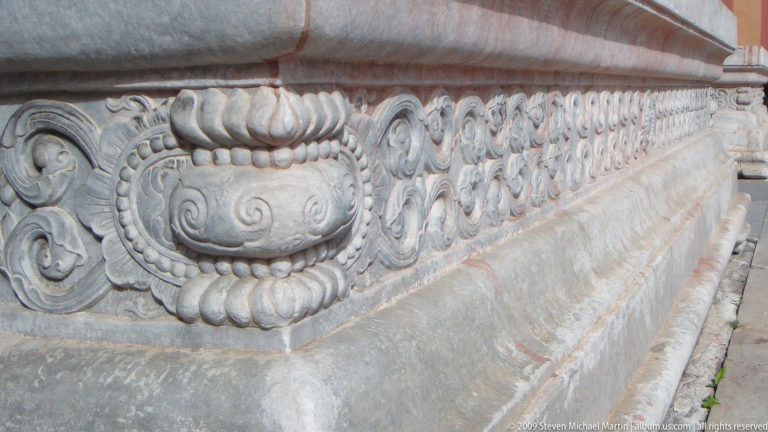 Carved stone terrace base with lotus and ruyi scroll relief in shallow decorative panel.
