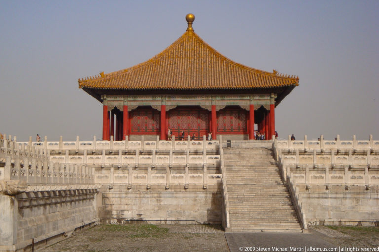 Frontal view of a small yellow-roofed imperial pavilion on multi-tiered white stone terraces with a central stairway in the Forbidden City.
