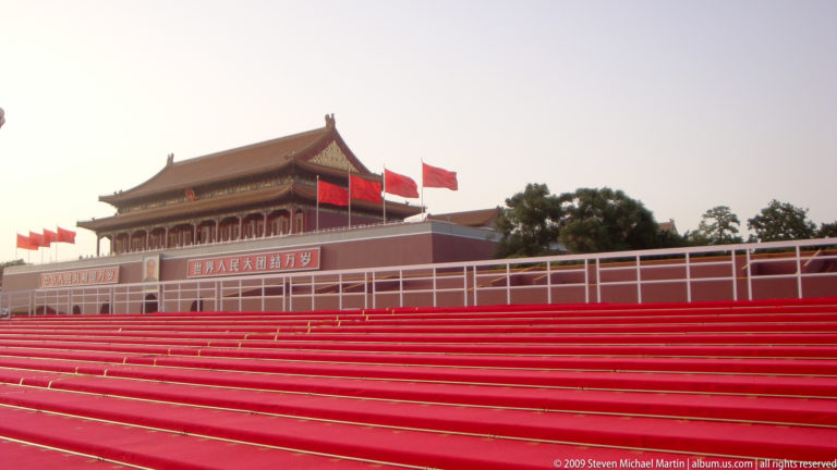 Tiananmen Gate in Beijing with long rows of bright red temporary seats set up in front.