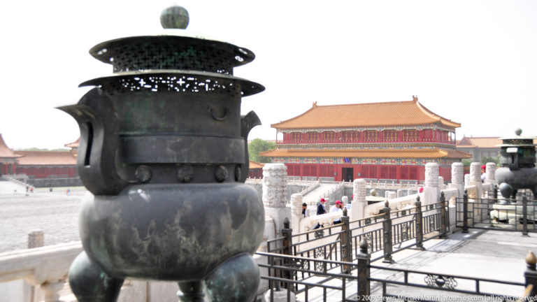 Large tripod bronze bronze incense burner with tall pierced canopy in front of a palace hall in the Forbidden City.