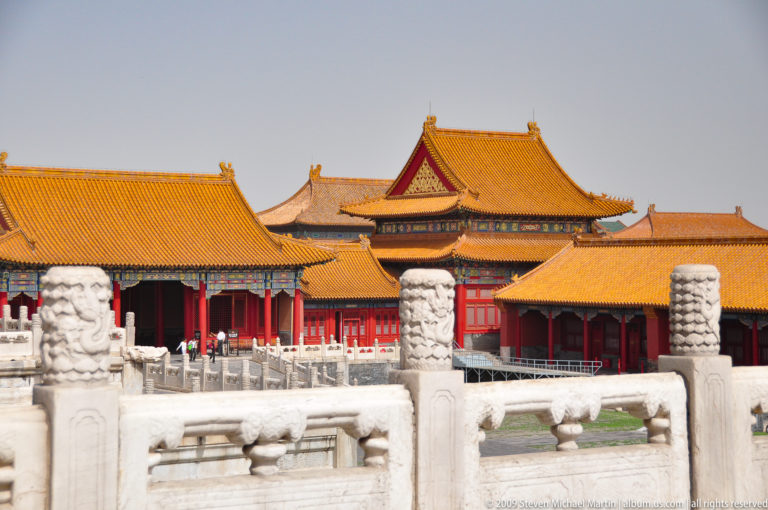 Telephoto view of the Forbidden City showing overlapping yellow-roofed halls behind carved white stone balustrades.