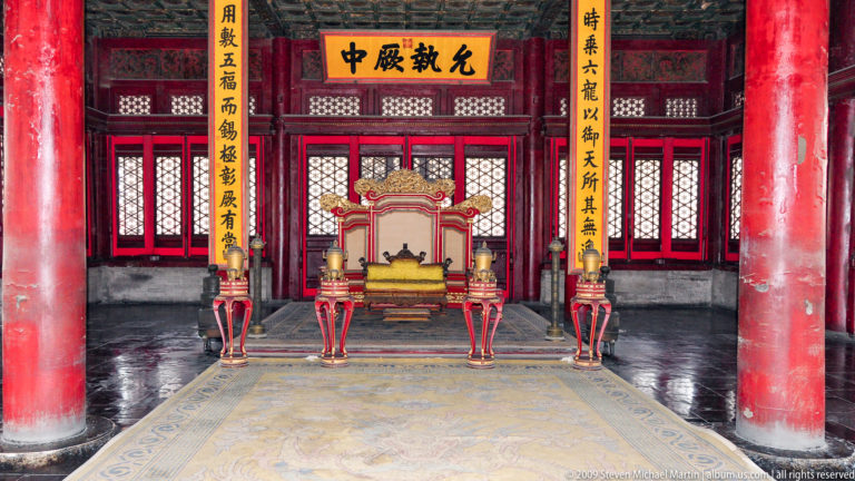 Frontal view of an imperial throne in the Forbidden City beneath a yellow plaque inscribed with the characters 允执厥中, flanked by vertical calligraphy panels.