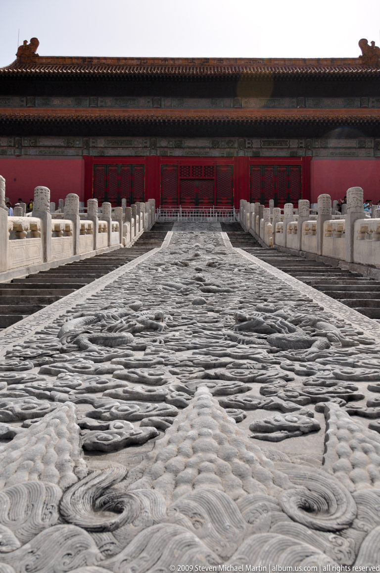 Axial view up the carved imperial dragon ramp flanked by parallel stone stairways in the Forbidden City.