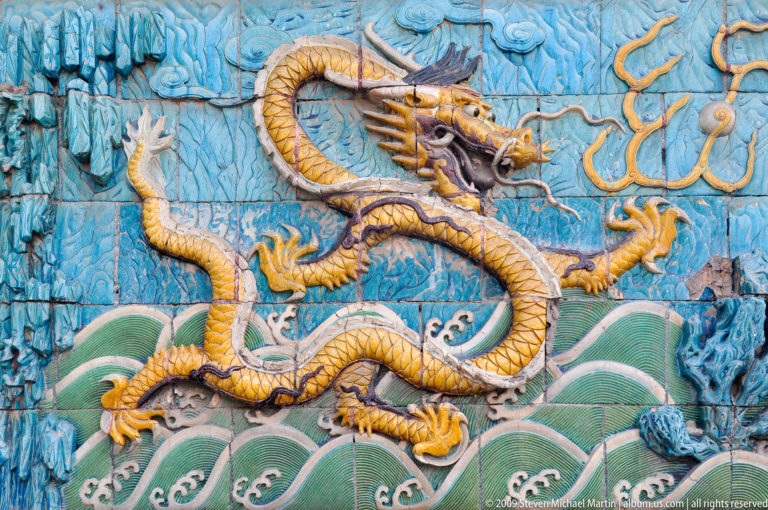Glazed ceramic panel showing a five-clawed yellow dragon above green waves on a turquoise background from the Nine-Dragon Screen in the Forbidden City.