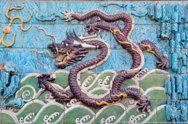 Glazed ceramic panel showing a purple five-clawed dragon above stylized green waves on a turquoise background from the Nine-Dragon Screen in the Forbidden City.