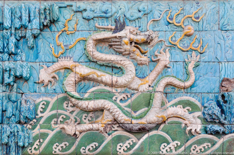 Glazed ceramic panel showing a five-clawed white dragon above stylized green waves on a turquoise background from the Nine-Dragon Screen in the Forbidden City.