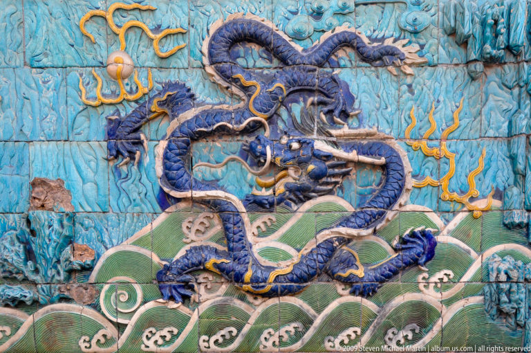 Glazed ceramic relief of a five-clawed blue dragon above stylized green waves on a turquoise background, from the Nine-Dragon Screen in the Forbidden City.
