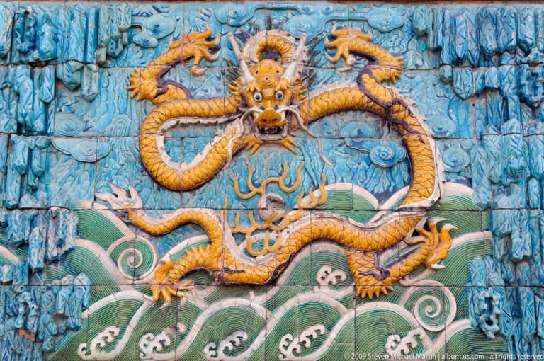 Glazed ceramic panel showing a five-clawed yellow dragon above stylized green waves from the Nine-Dragon Screen in the Forbidden City.