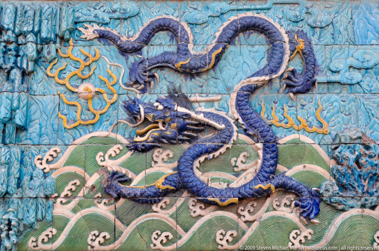 Glazed ceramic panel showing a five-clawed blue dragon above stylized green waves on the Nine-Dragon Screen in the Forbidden City.