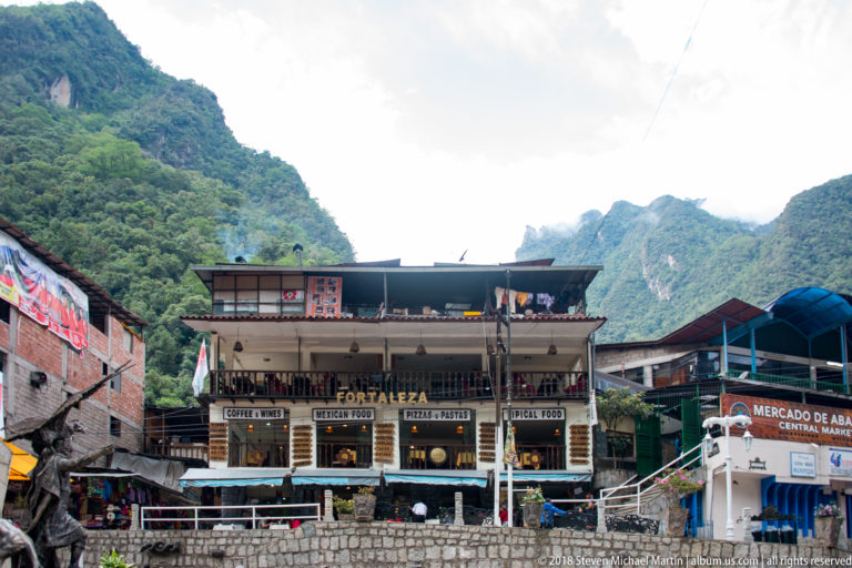 La Fortaleza building and Mercado de Abasto Central beneath steep green mountains in Aguas Calientes.