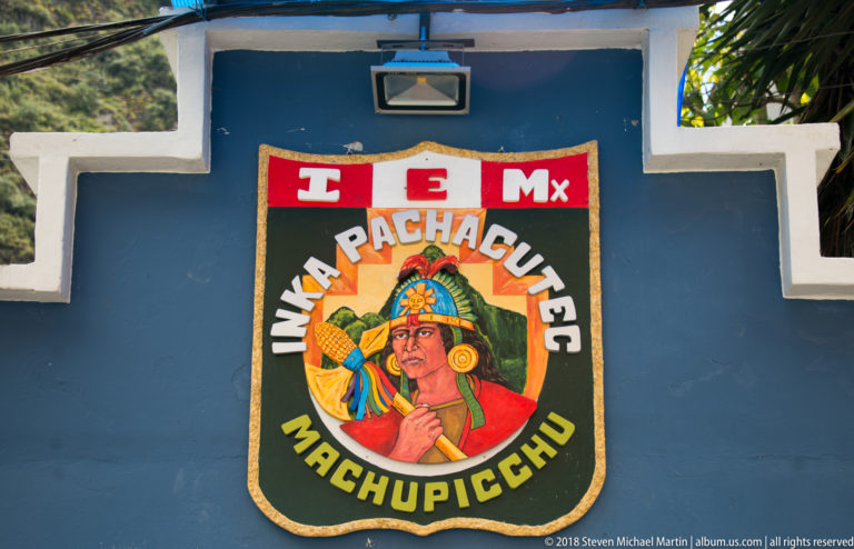 Colorful wall emblem reading “Inka Pachacutec Machupicchu” with a stylized Inca portrait on a blue background.