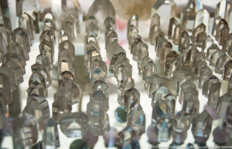 Rows of small polished stone human figurines arranged closely on a shop display, with foreground carvings in sharp focus.