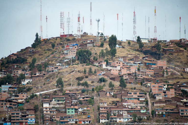 Dry Cusco hillside crowded with houses and numerous communications towers along the summit.