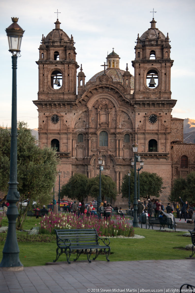 Iglesia de la Compañía de Jesús beyond lawns, flowers and benches in Cusco’s Plaza de Armas.