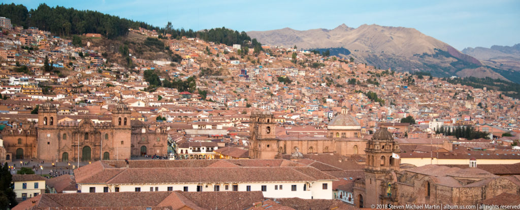 Cusco Cathedral and red-tiled historic-center roofs below a densely settled mountain slope.
