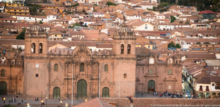 Cusco Cathedral with twin stone bell towers facing the Plaza de Armas, backed by densely built hillsides.