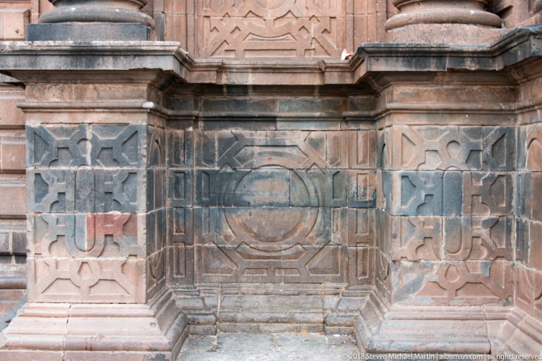 Close stone façade detail with carved geometric panels and central octagonal relief motif.
