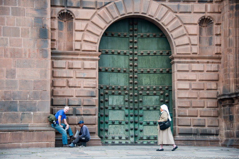 Large green double doors studded with metal bosses within a rusticated stone arch.