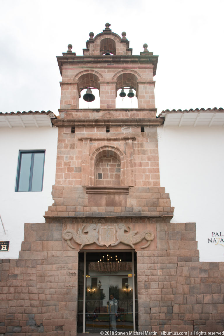 Stone façade topped by two bell openings and a shaped pediment above a historic entrance.