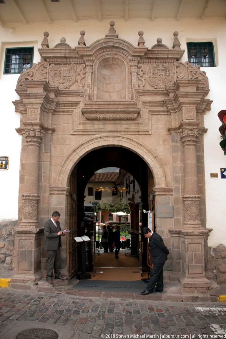 Large carved stone portal with arched entrance, columns, relief ornament, and two attendants.