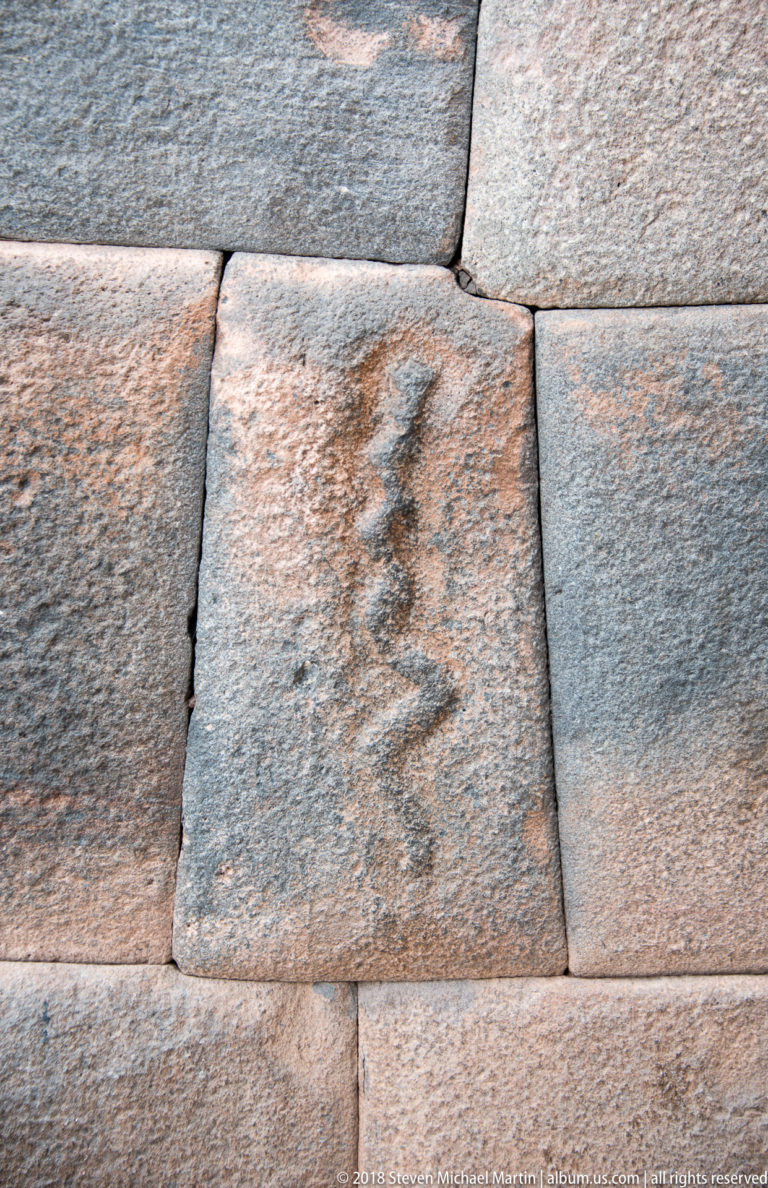 Close view of tightly fitted stone blocks, one bearing a dark vertical surface marking.