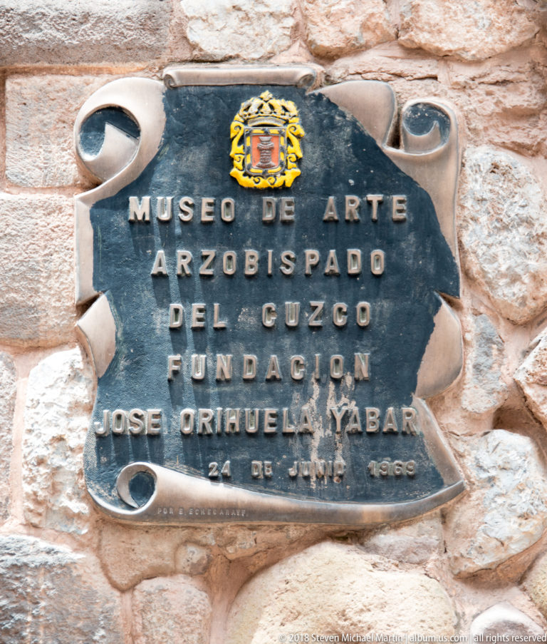 Dark metal plaque reading Museo de Arte Arzobispado del Cuzco with a heraldic emblem.