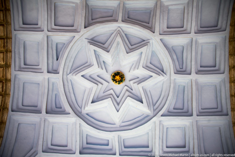 White coffered ceiling centered on an eight-pointed star with a small gilded floral boss.