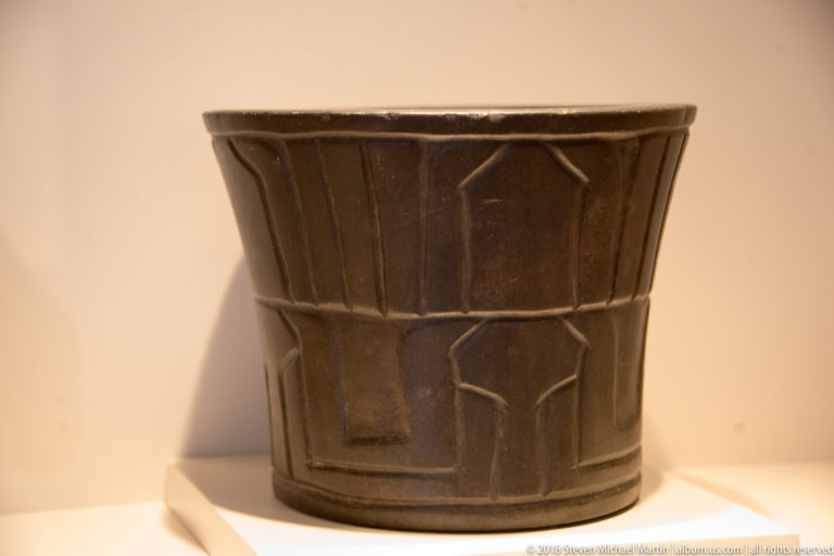 Cupisnique cylindrical stone mortar carved with geometric relief around its sides.