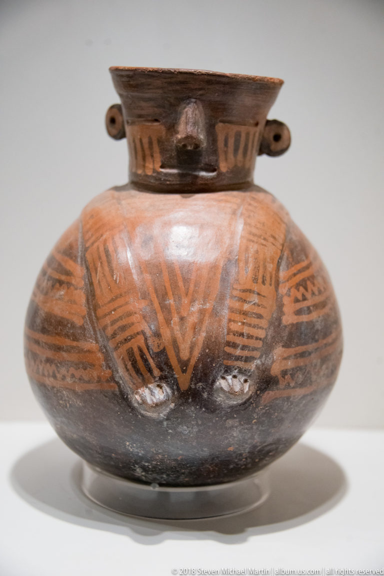 Virú globular ceramic bottle with modeled human face, projecting ears, and rounded body.