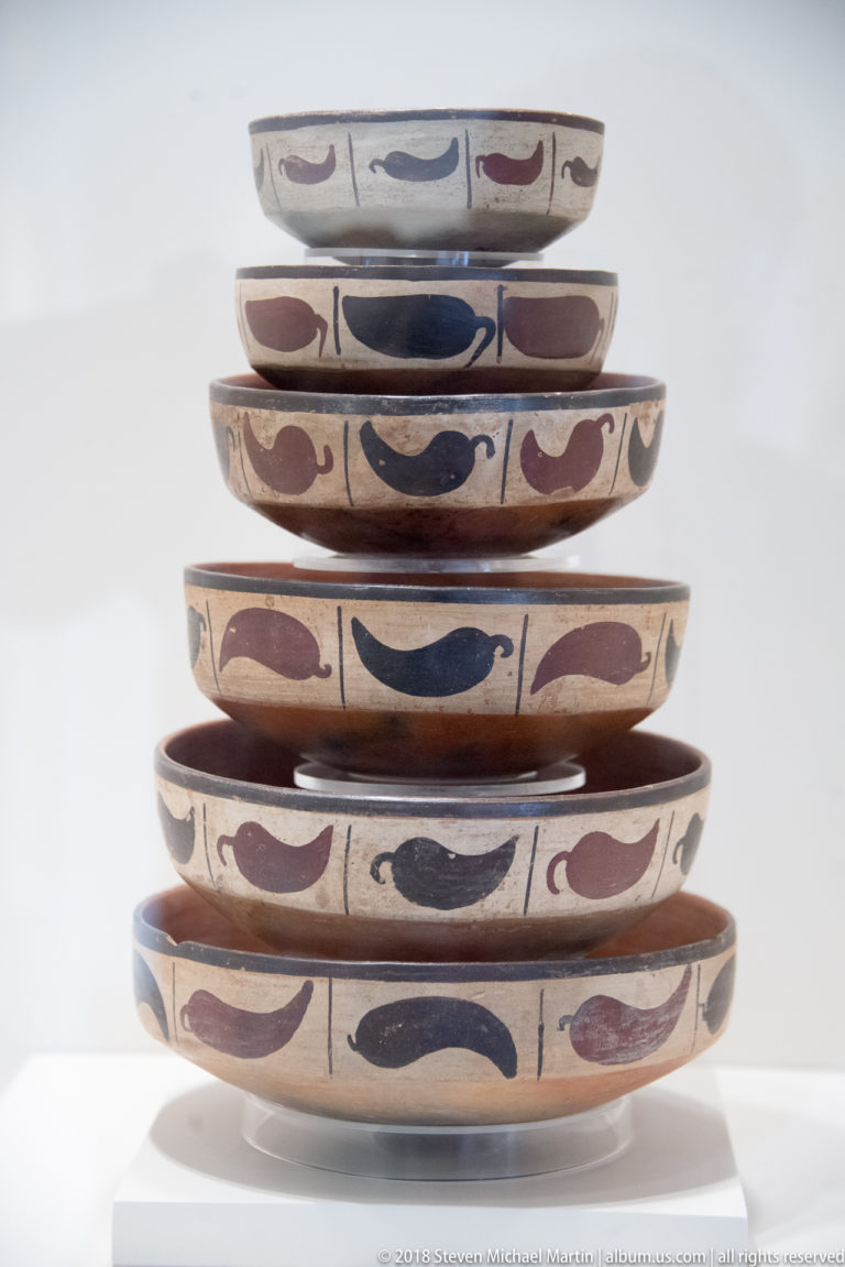 Nasca graduated stack of shallow ceramic bowls with cream surfaces and repeating dark red and black curved motifs.