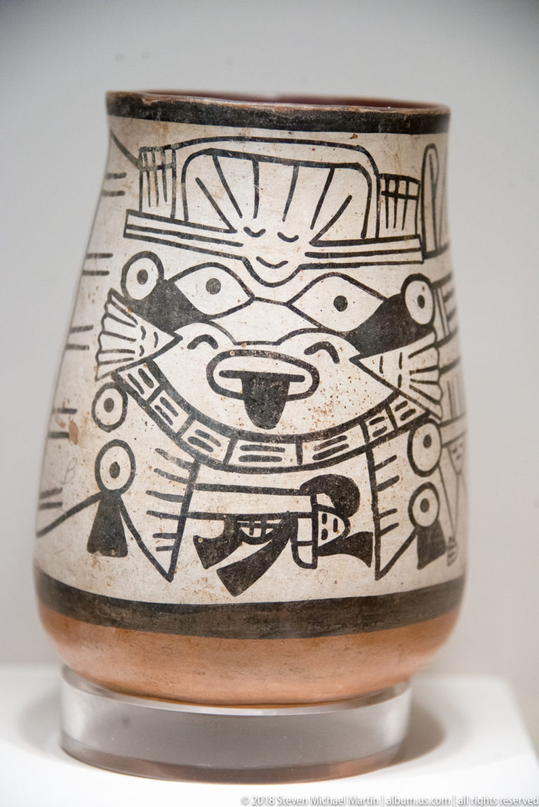 Nasca low cream ceramic bowl with black painted frontal face, bird-like side figures, and dense geometric ornament.