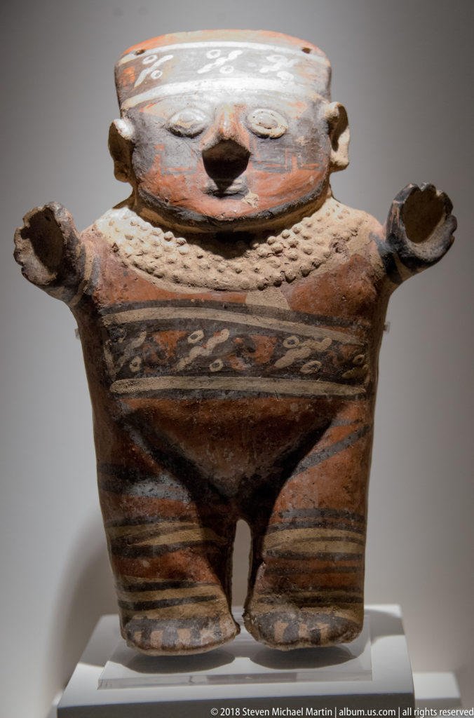 Large pre-Columbian ceramic human-effigy vessel with broad head, outstretched arms, separated legs, and painted geometric decoration.
