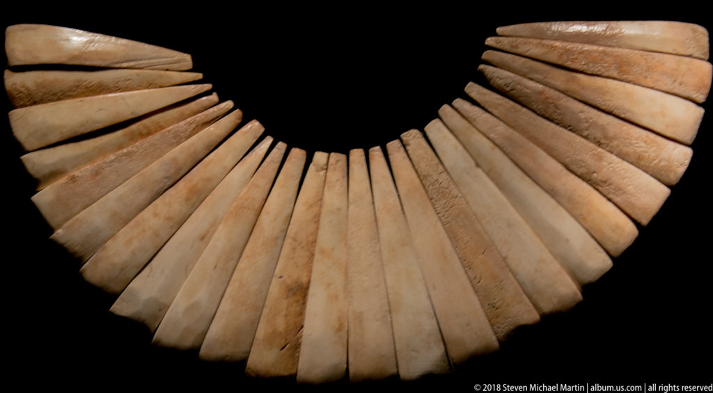Fan-shaped pre-Columbian collar of long pale rectangular shell plaques pierced at the top and arranged in a dense fringe.
