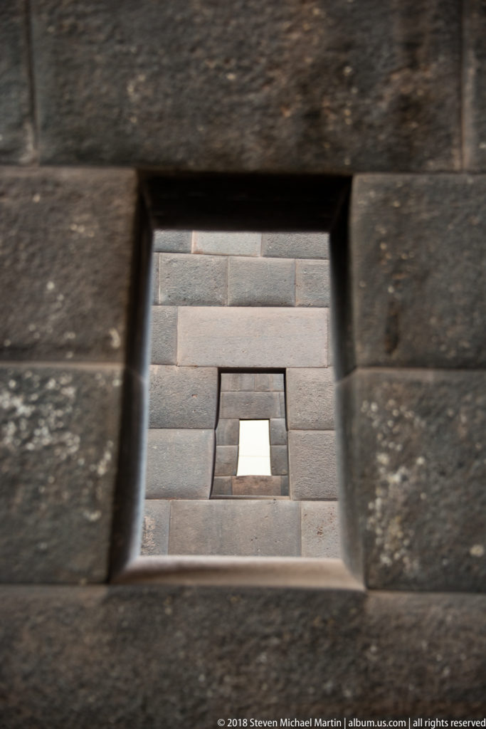 Several aligned trapezoidal stone doorways receding through dark Inca masonry walls.