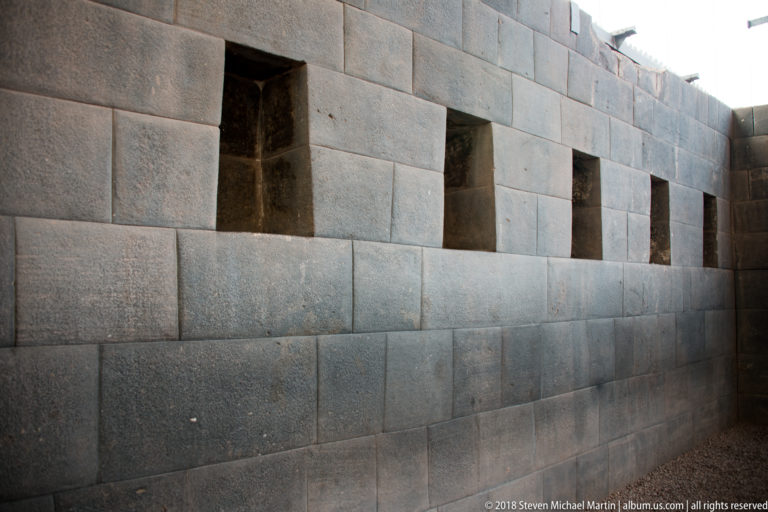Oblique view of an Inca stone wall with a row of deep trapezoidal niches.