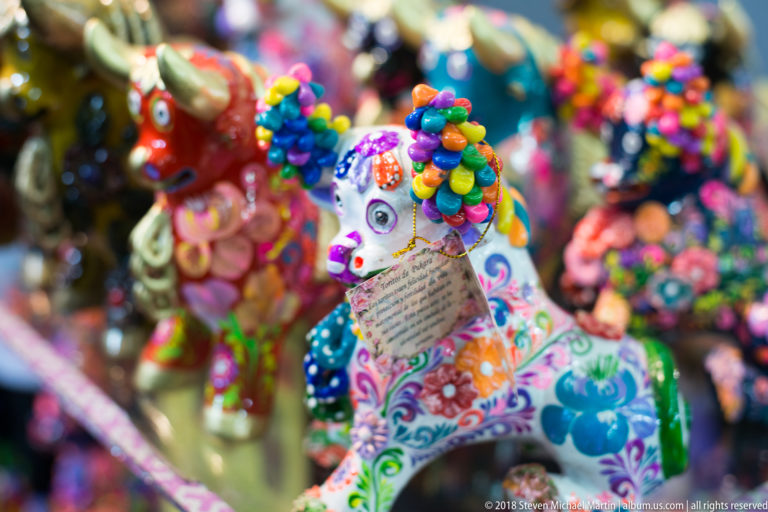 Colorfully decorated ceramic bull figurine with floral patterns and raised multicolored ornaments among other crafts.