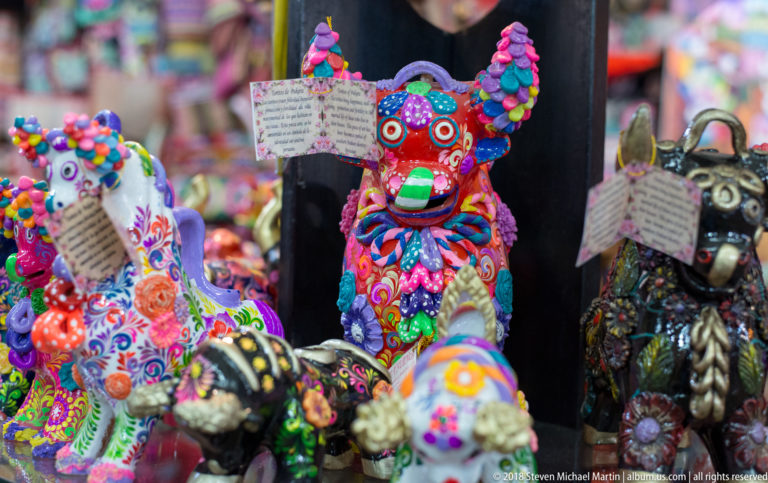 Cluster of vividly decorated ceramic bull figurines with multicolored raised ornament in a Cusco craft market.